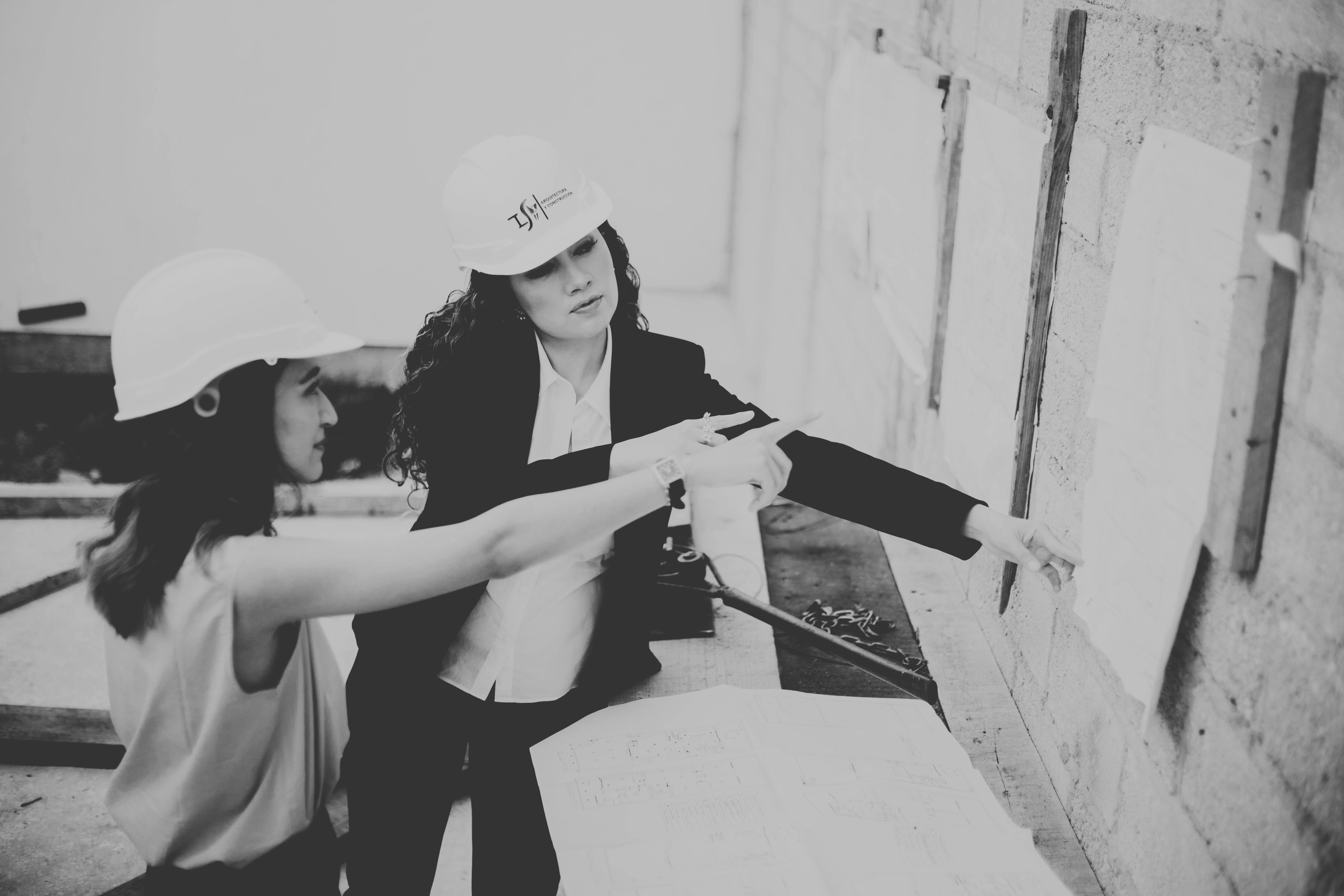 Two female commercial construction project managers from Build Solutions reviewing architectural blueprints on a Los Angeles job site, showcasing woman-owned general contracting expertise.