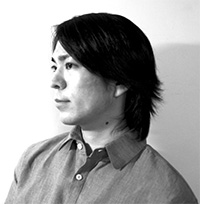 Yota Kobayashi with medium-length dark hair wearing a button-up shirt is shown in black-and-white, facing left in a side profile view.