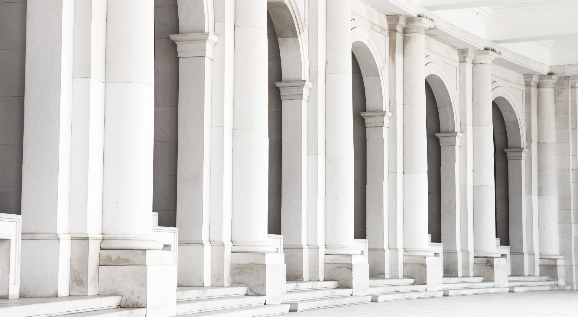 Long row of white stone columns and arches in a government building corridor.