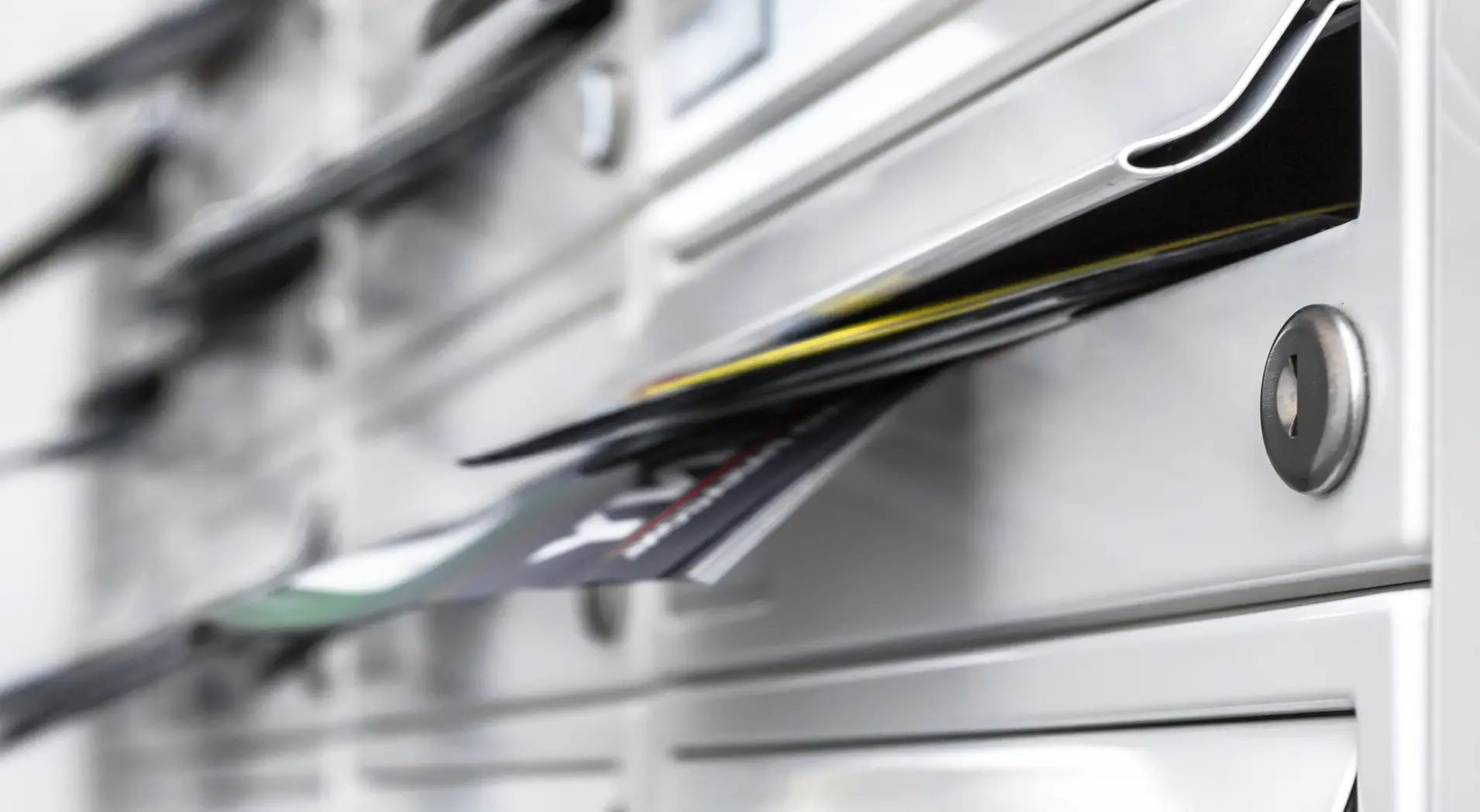 Metal mailbox with envelopes and papers partially inserted in the mail slot.