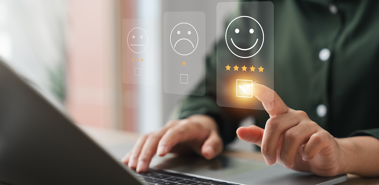 Person using a laptop and selecting a five-star happy face rating on a digital sentiment analysis interface.