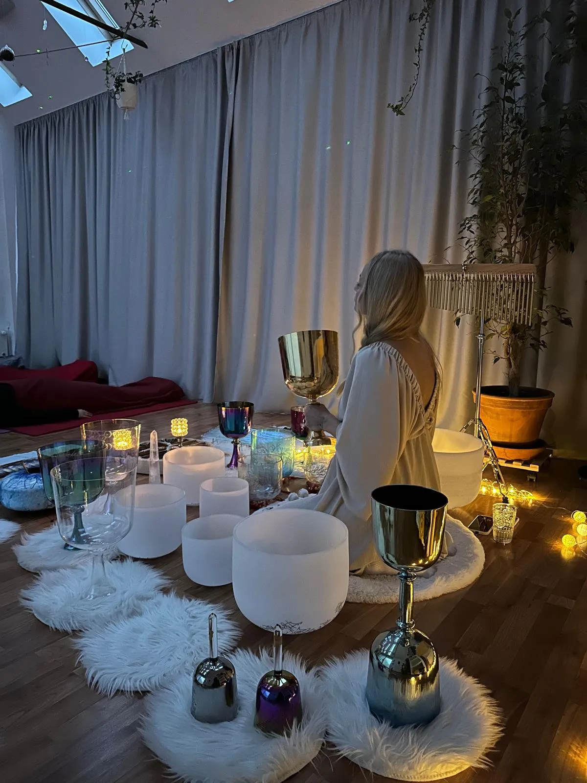 Joga štúdio v Košiciach s presvetleným interiérom, drevenou podlahou a farebnými joga podložkami. Veľké okná a strešné svetlíky prinášajú prirodzené svetlo do miestnosti, ktorá je zdobená zeleňou a spirituálnymi symbolmi.