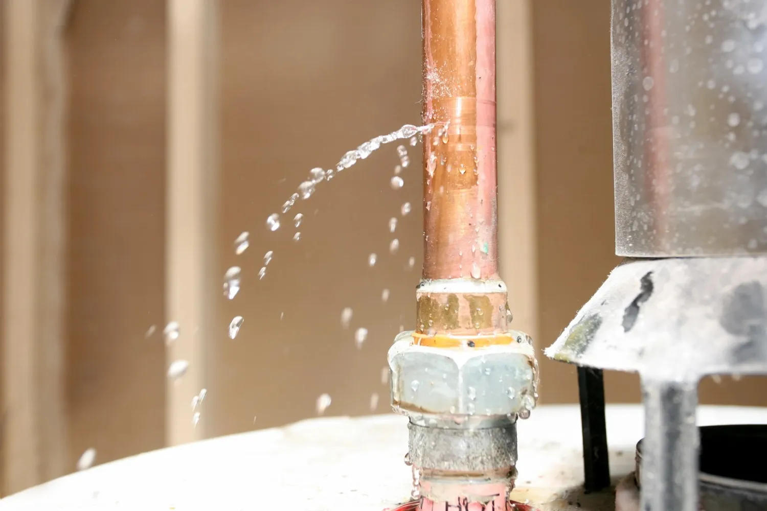 A close-up of a copper pipe with a leak, spraying water from a connection.