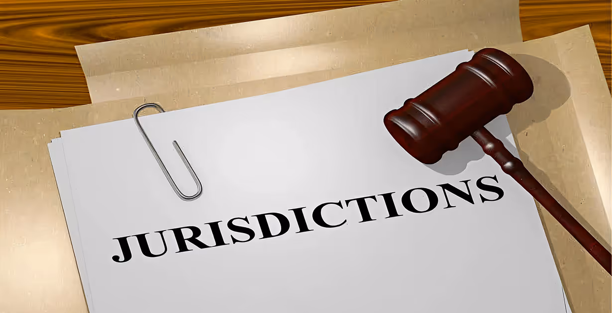 Stack of documents labeled “JURISDICTIONS” with judge’s gavel on wooden surface, symbolizing legal authority.