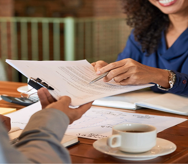 Two professionals sitting at a table, reviewing documents with a clipboard and pen