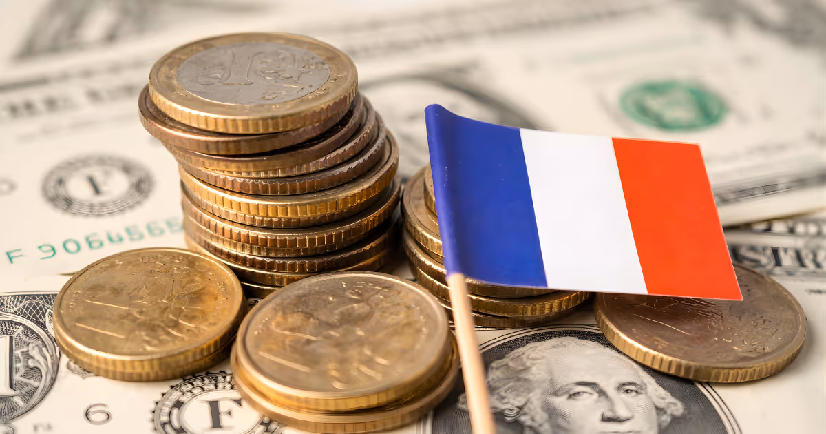 Euro coins and a French flag resting on US dollar banknotes