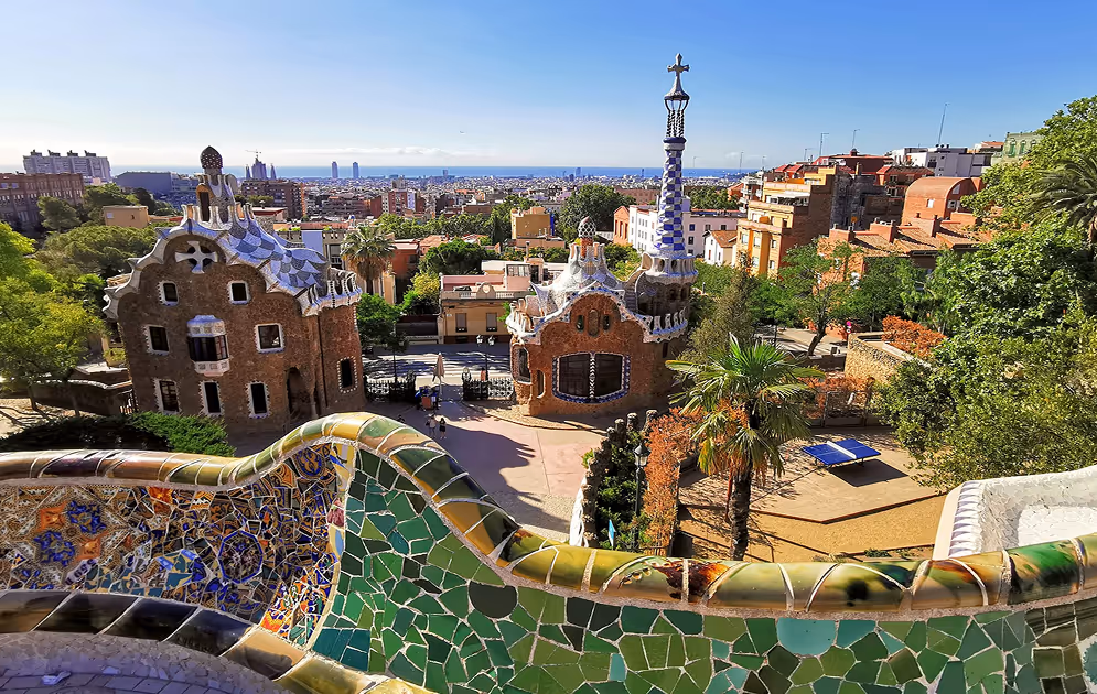 Colorful mosaic bench at Park Güell with Gaudí architecture and panoramic view of Barcelona and sea