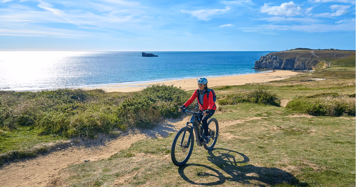 Active retiree riding her  electric mountain bike along the wild coast of Finisterre in southern Brittany, France