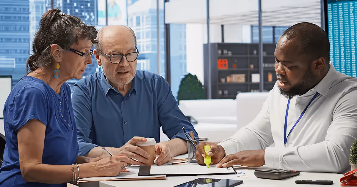 Senior couple meeting with a financial advisor in a modern office, reviewing retirement plans and investment documents together.