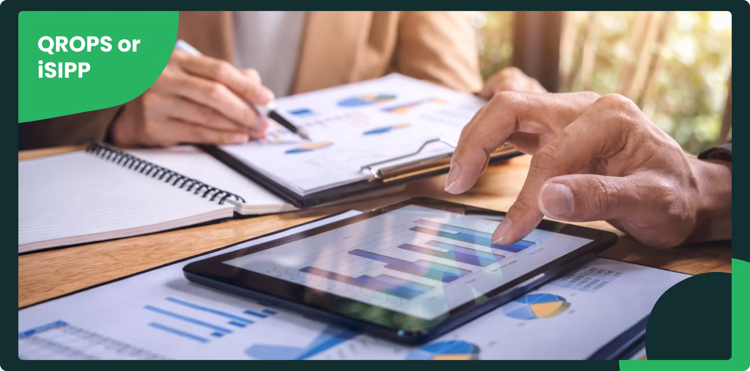Close-up of hands reviewing financial charts on a tablet during a business meeting, with documents and graphs spread across a desk