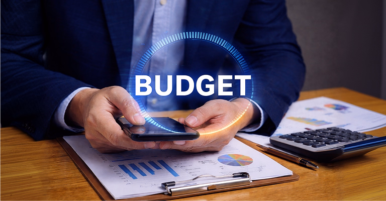 Business professional using a smartphone over financial reports with a digital budget interface