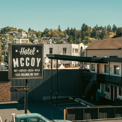 A large, vintage black and white sign for Hotel McCoy in Pullman, WA, standing in front of a classic two-story motel building.
