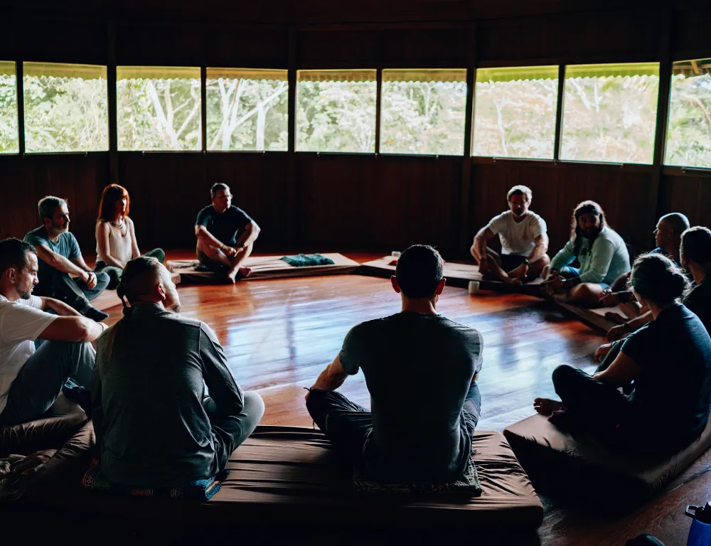 A group sitting in a circle on the floor of a wooden hall