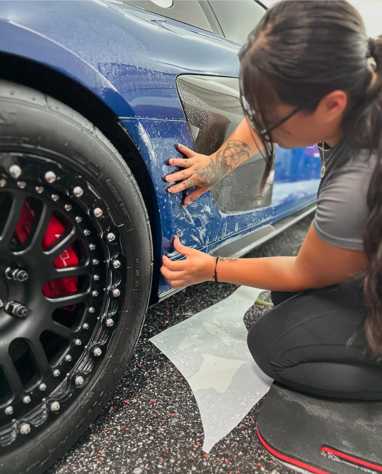 Allure co-founder Leila applying paint protection film to a Blue Audi R8 with blacked out wheels and red calipers at Allure Auto Spa in Casselberry, Florida