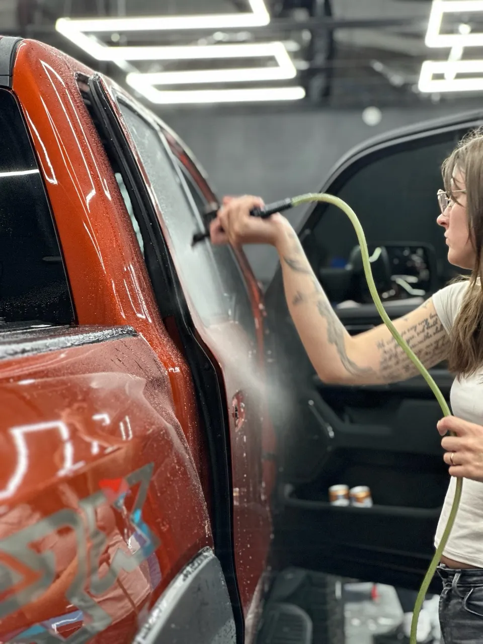 Orange pickup truck being detailed by female team member at Allure Auto Spa