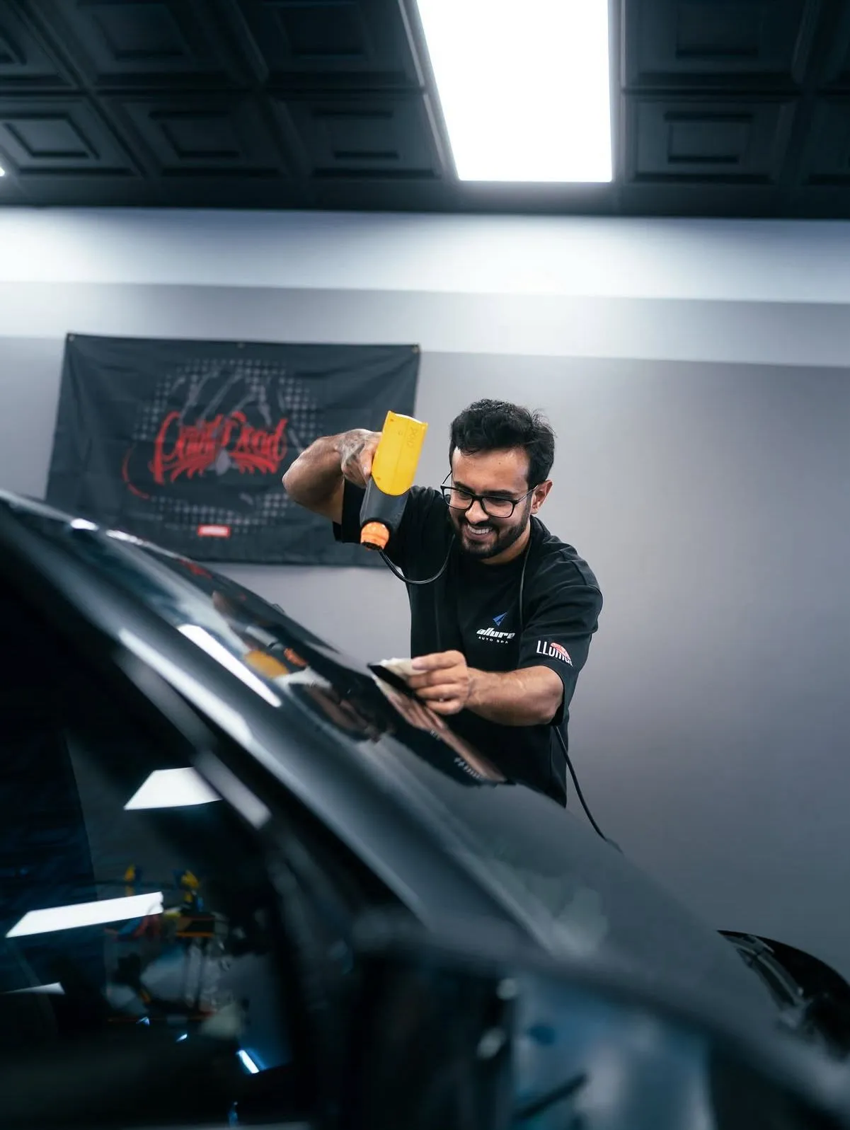 Allure Auto Spa installer heat-shrinking window tint on a black car rear glass, Fern Park FL