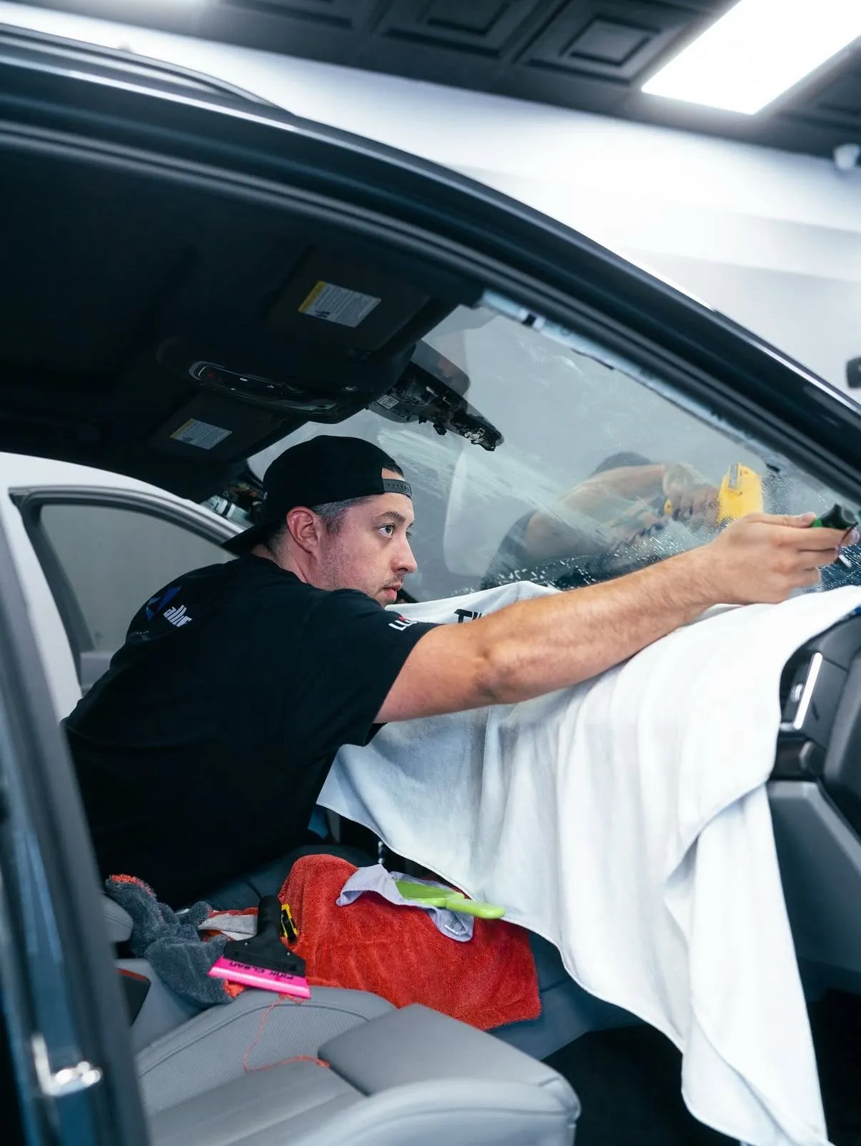 Allure Auto Spa technician installing window tint on a car front windshield interior, Winter Park FL