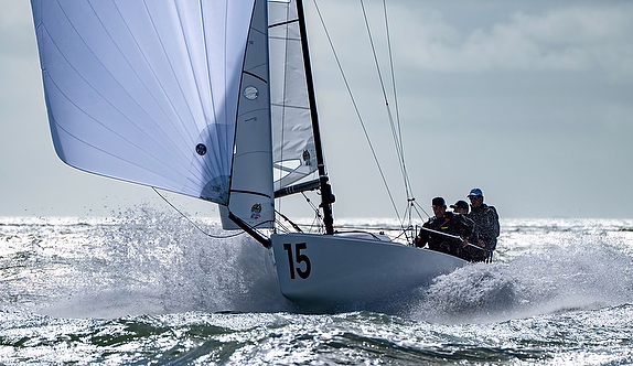 A J/70 keelboat throwing spray as it races upwind