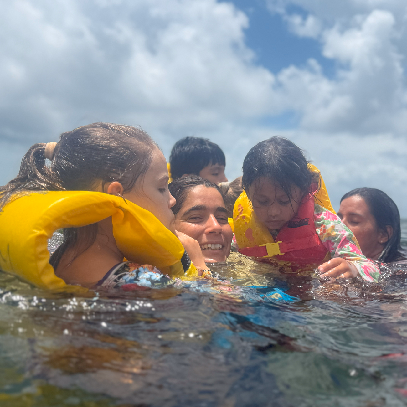Young participants in life vests laughing together in the shallow water