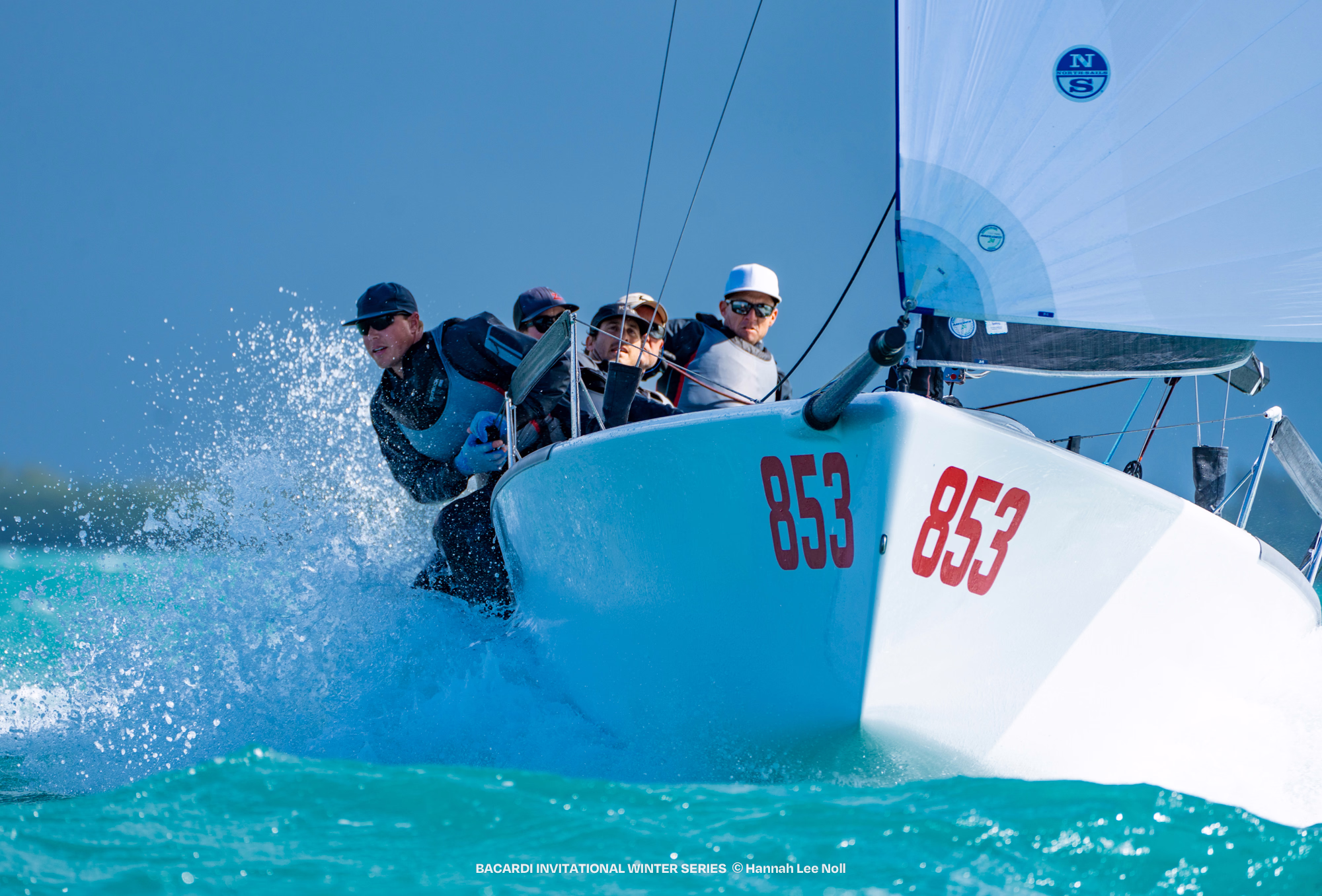 A keelboat heeling hard with its crew hiked out over the rail