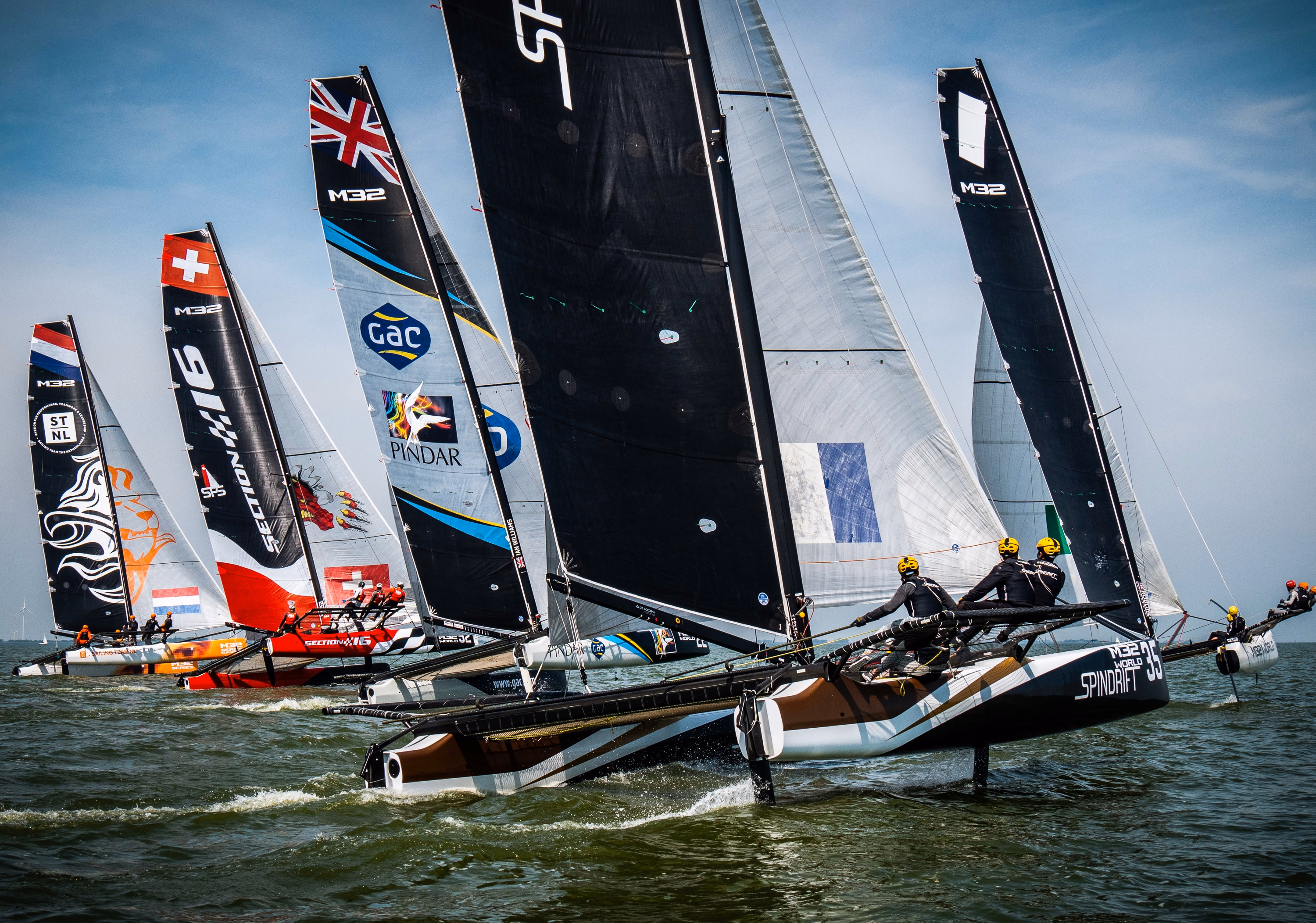 An M32 catamaran at full speed with its crew out on the wing