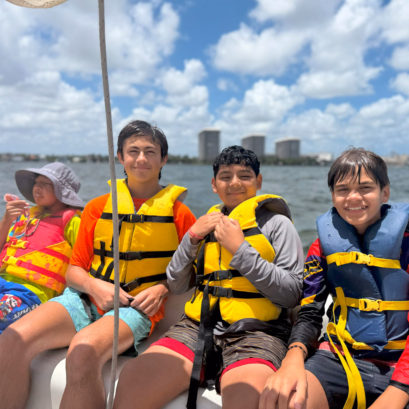 Three boys sailing by skyline