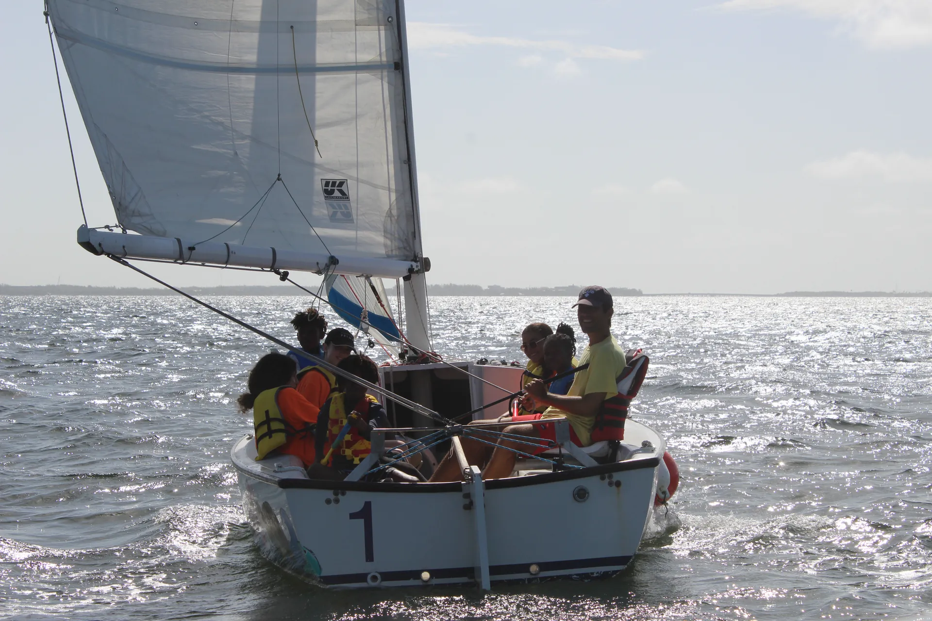 A keelboat under sail with several people aboard
