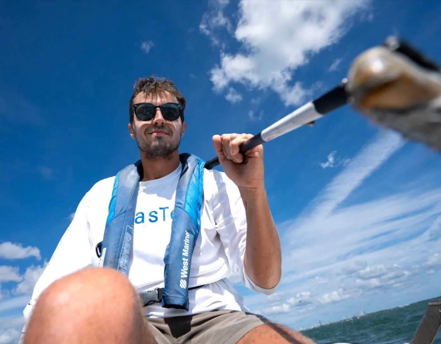 A participant in a life vest aboard a boat on a bright day