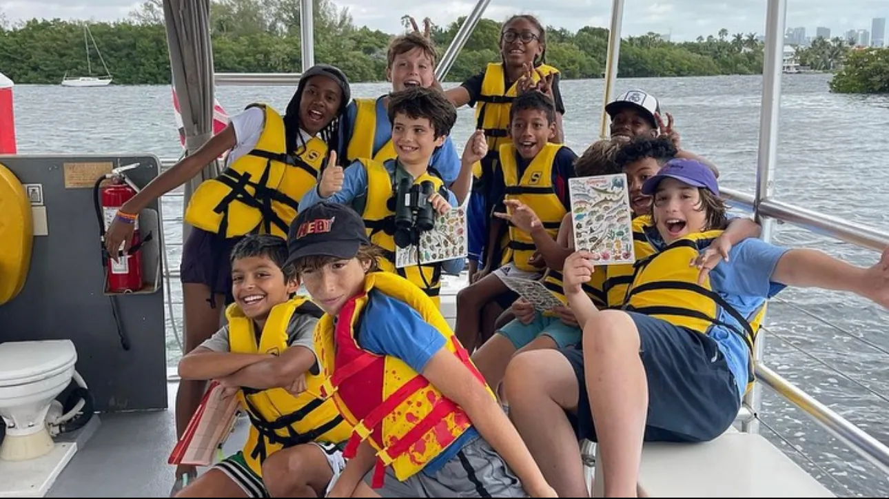 Students in life vests aboard a boat beside the mangroves
