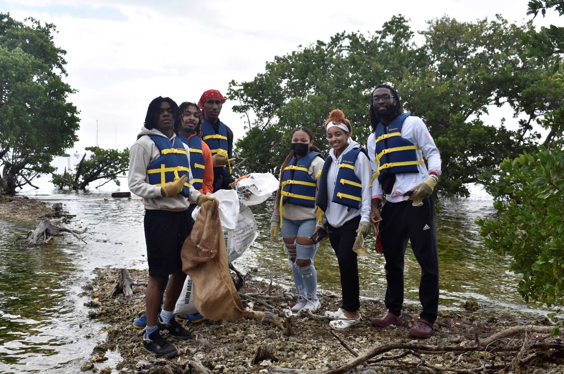 Volunteers in life vests with bin bags after a mangrove clean-up