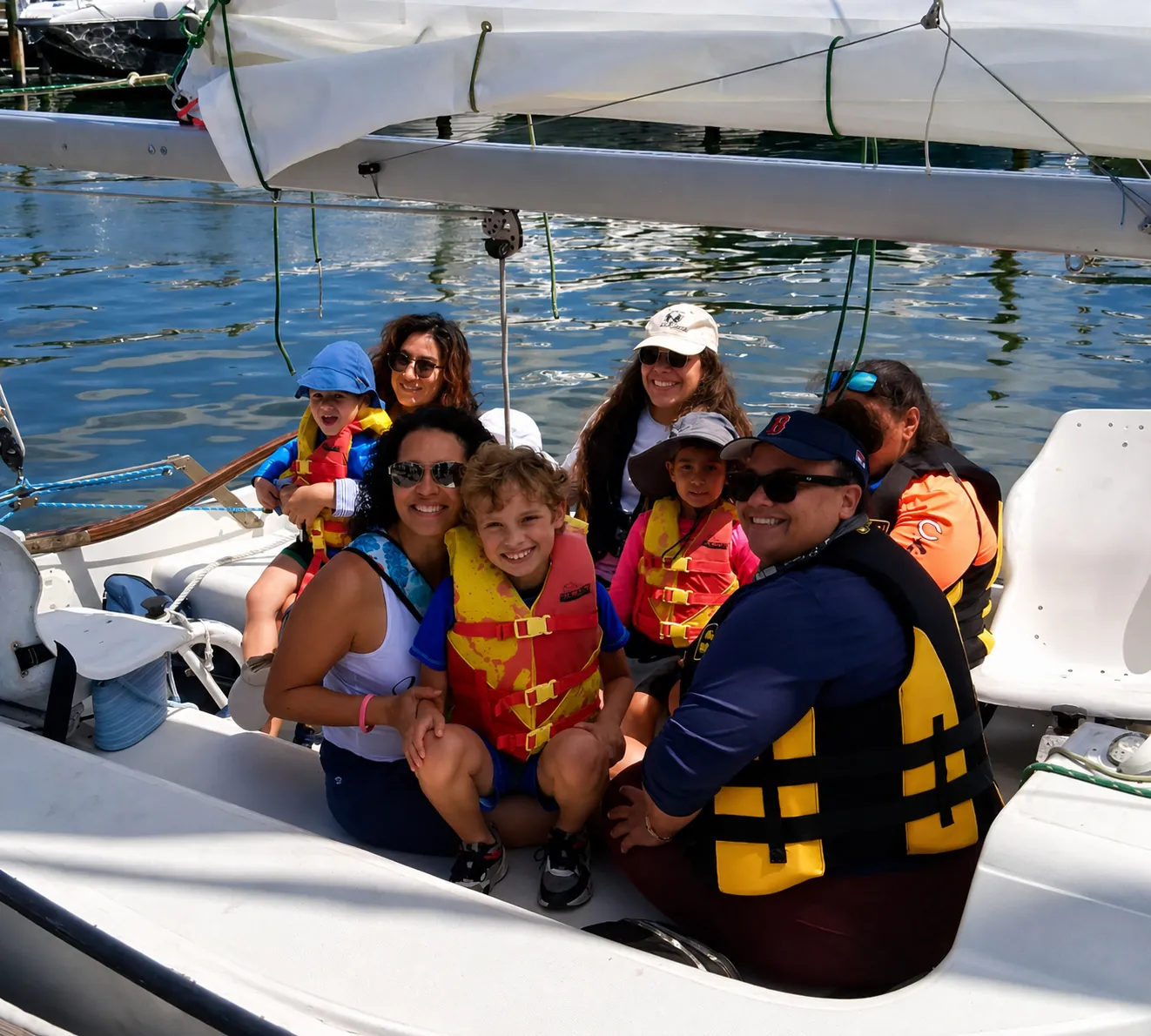 Participants in life vests packed together aboard a sailboat