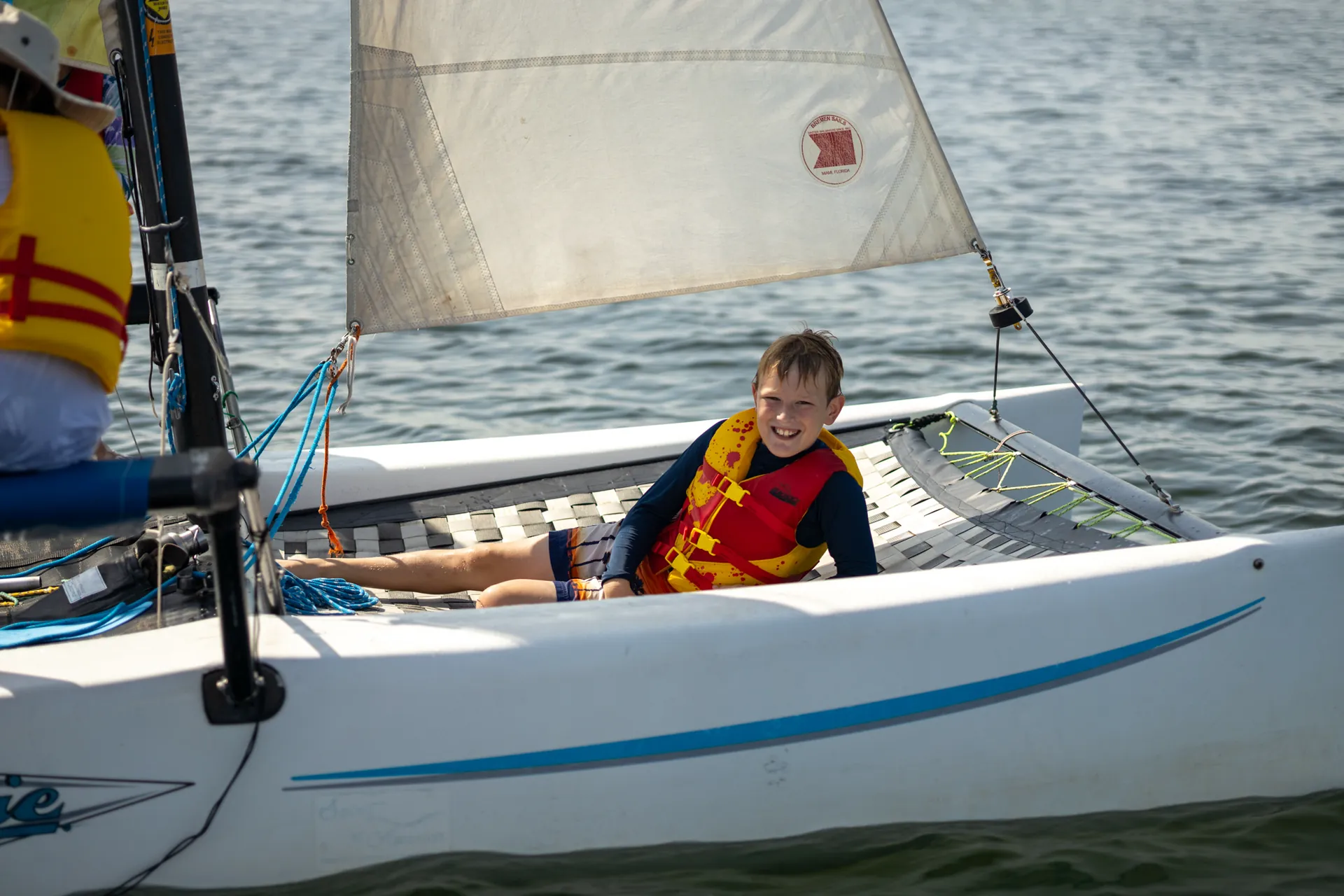 A young sailor in a life vest sailing a small boat