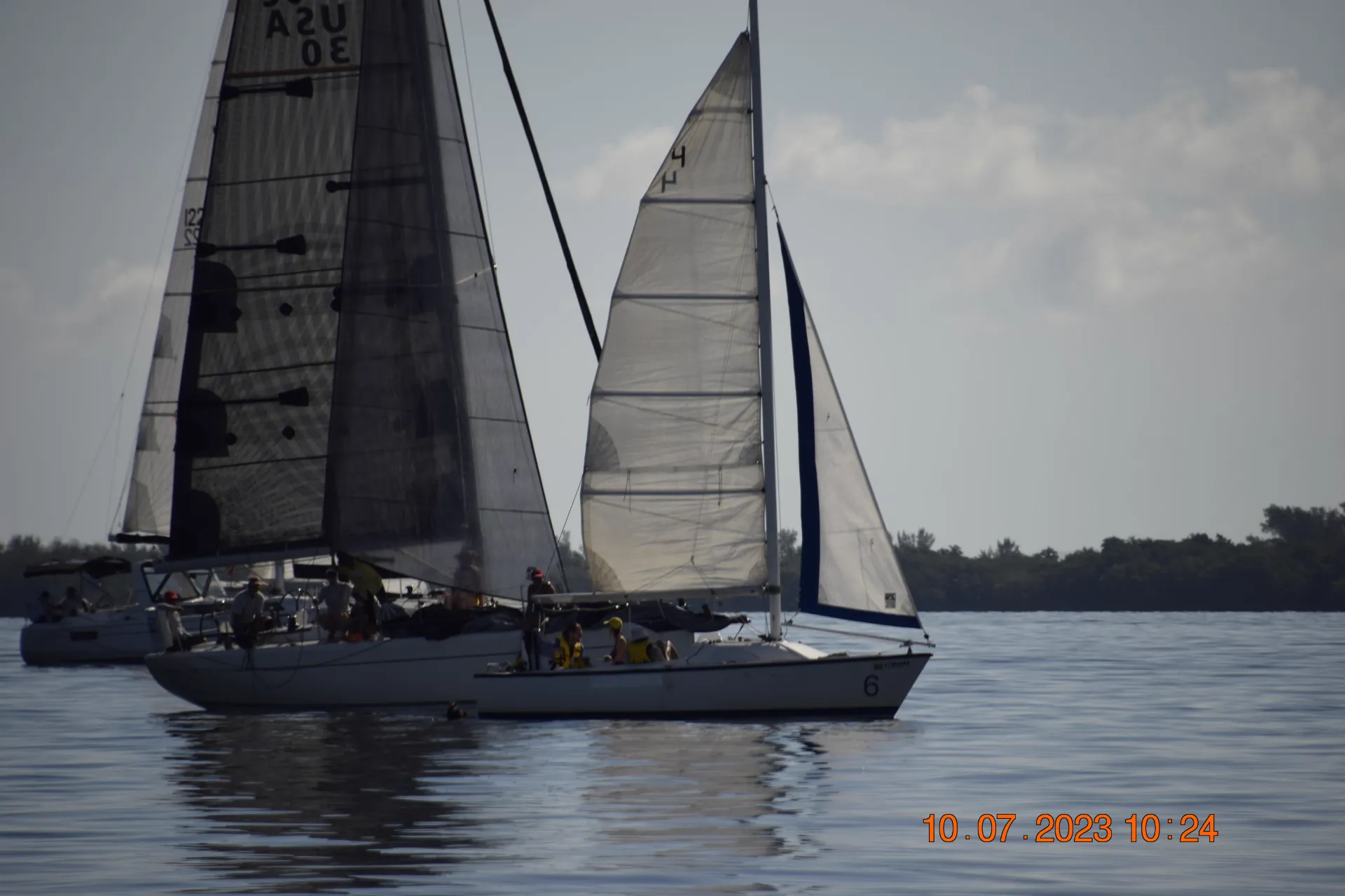 Two sailboats racing close together on the bay