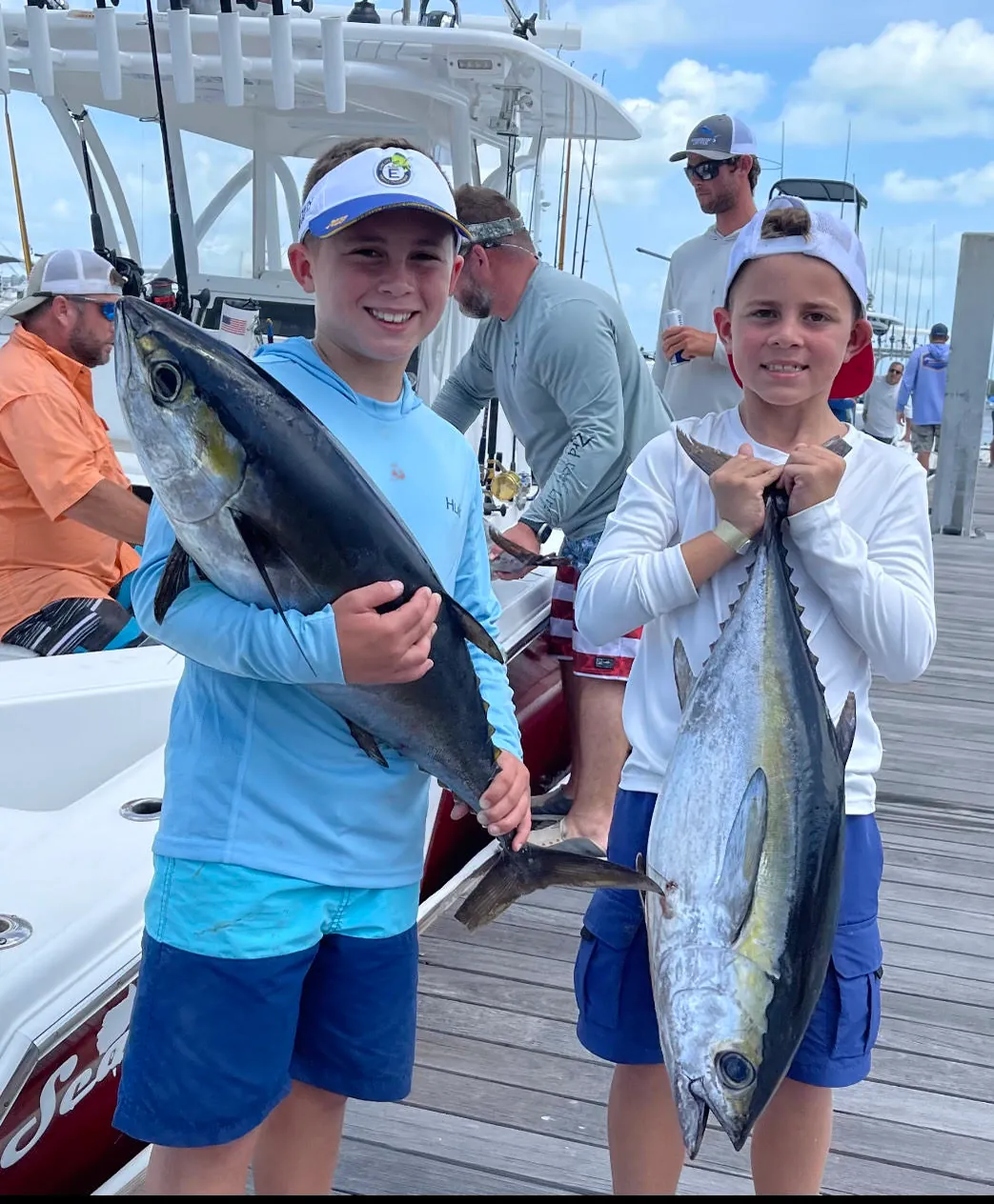 Two young anglers holding up the tuna they caught on the dock