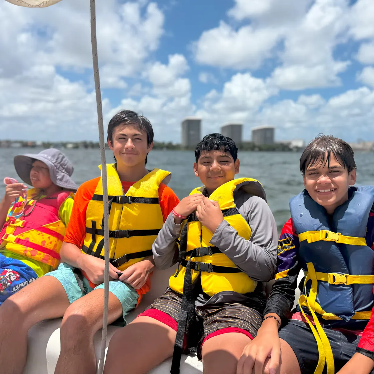 Four young participants in life vests on deck, the Miami skyline behind them