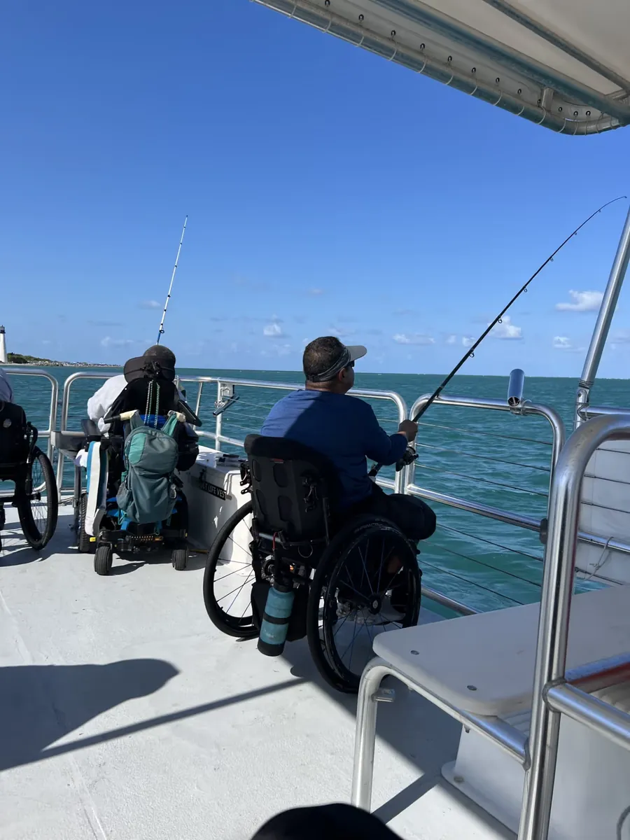 Two anglers in wheelchairs fishing from the deck of an accessible boat on Biscayne Bay