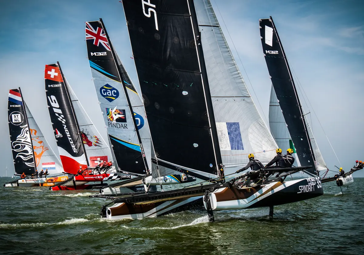 An M32 catamaran at full speed with its crew out on the wing
