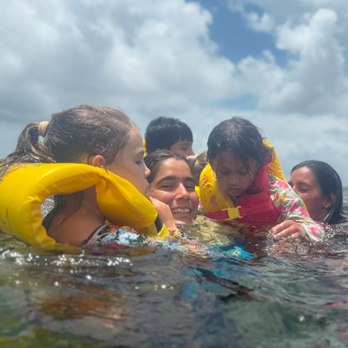 Young participants in life vests laughing together in the shallow water