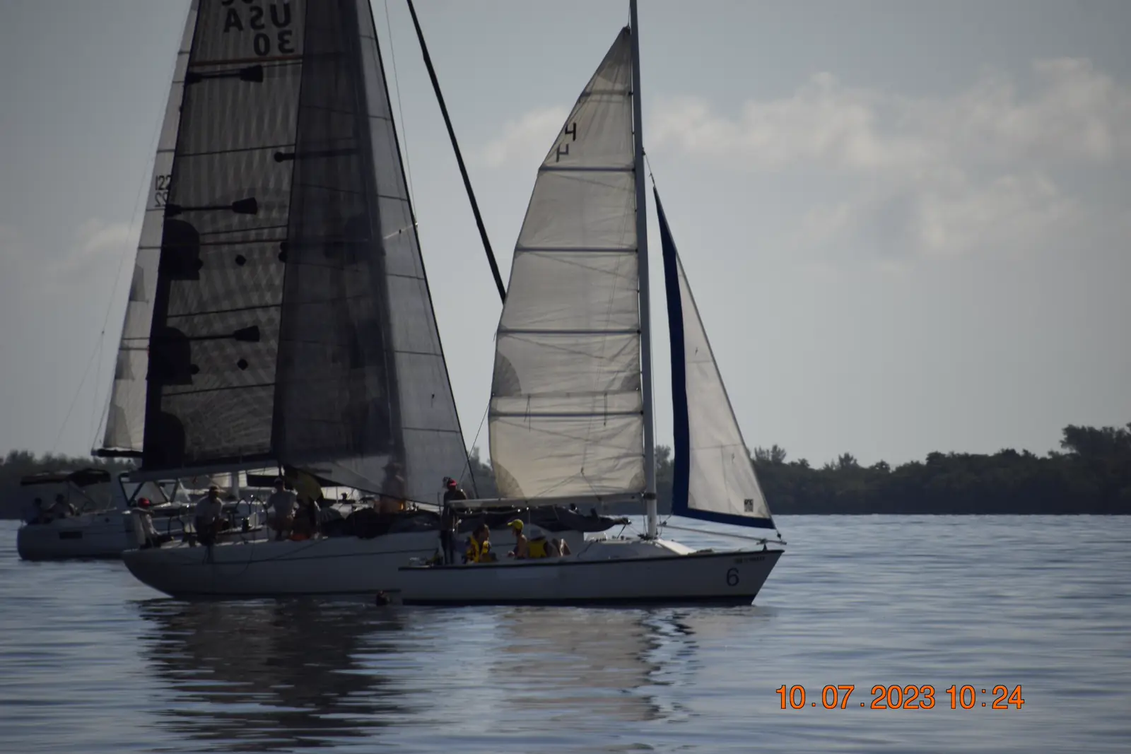 Two sailboats racing close together on the bay