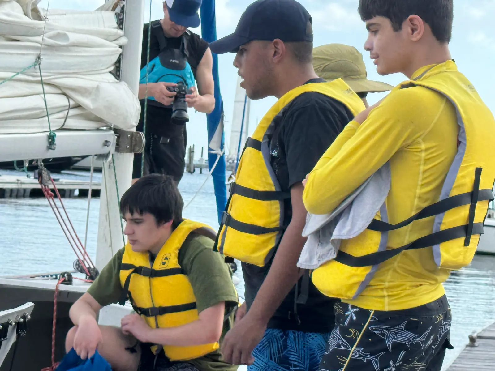 An instructor helping a young participant in a life vest at the dock