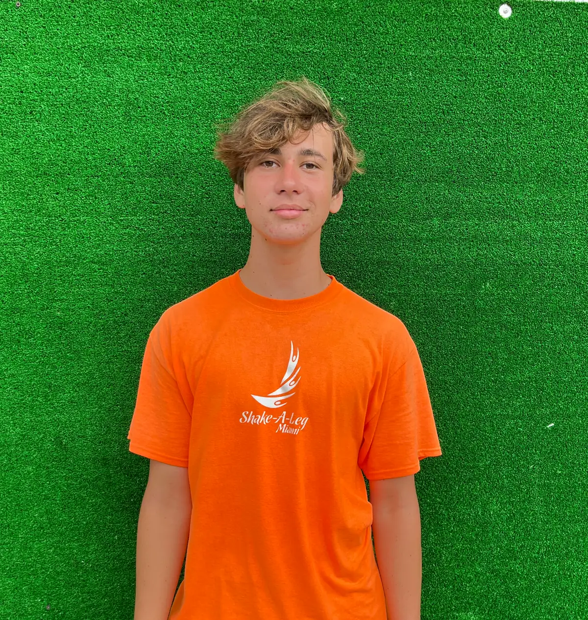 A teenage volunteer in an orange Shake-A-Leg Miami shirt
