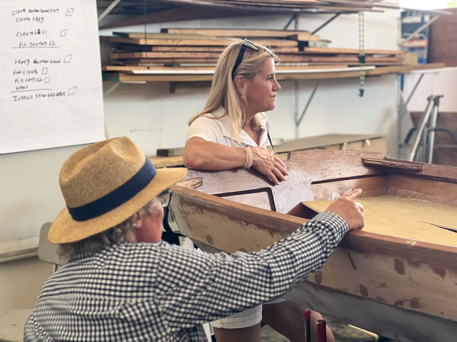 Two instructors working on a wooden boat hull in the shop