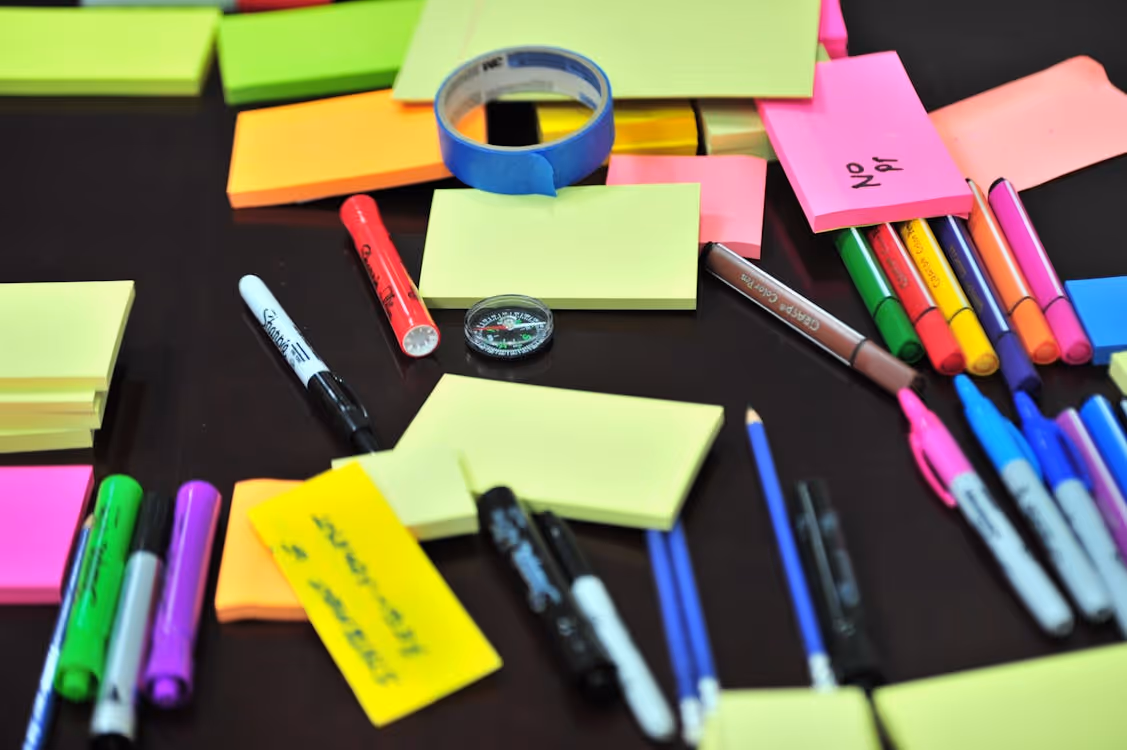 Free Photo of Sticky Notes and Colored Pens Scrambled on Table Stock Photo