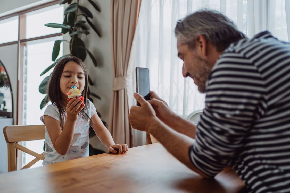 Free Father Taking Photo of Daughter Eating Cupcake Stock Photo