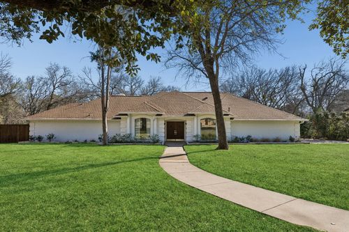 Two-story white stone home with cedar accents under live oaks, Mystic Oaks.