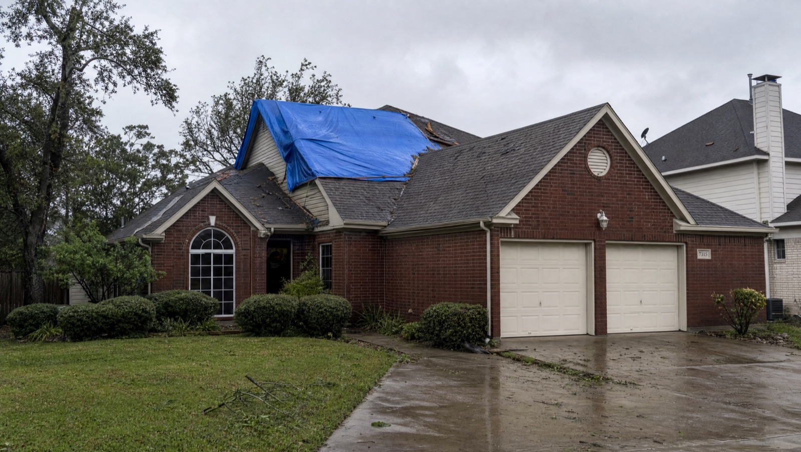 Home with a tarp-covered roof after storm damage