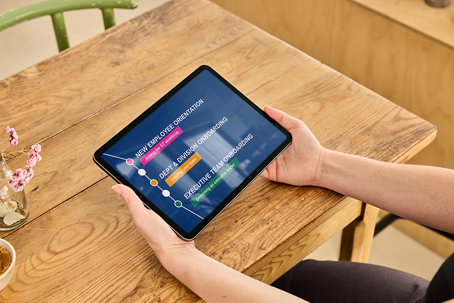 A person holds a tablet with an executive onboarding presentation displayed.