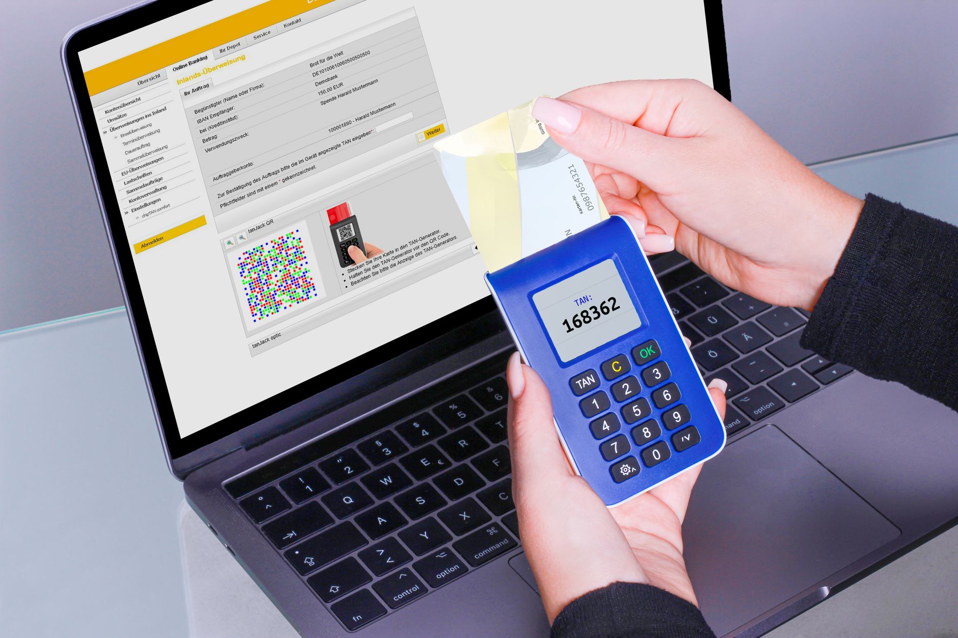 Hands using a hardware TAN-generator token alongside online banking on a laptop, representing stronger authentication than voice alone