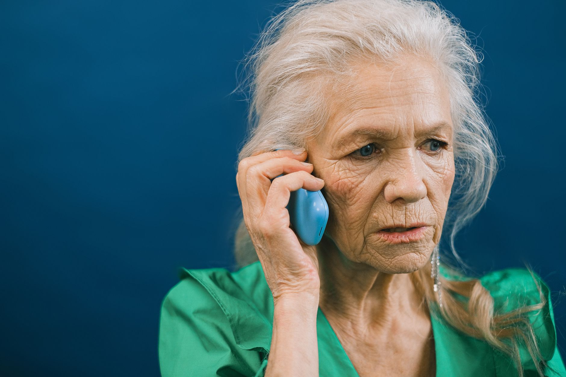 Elderly woman looking concerned while on a phone call, representing AI voice cloning fraud targeting seniors