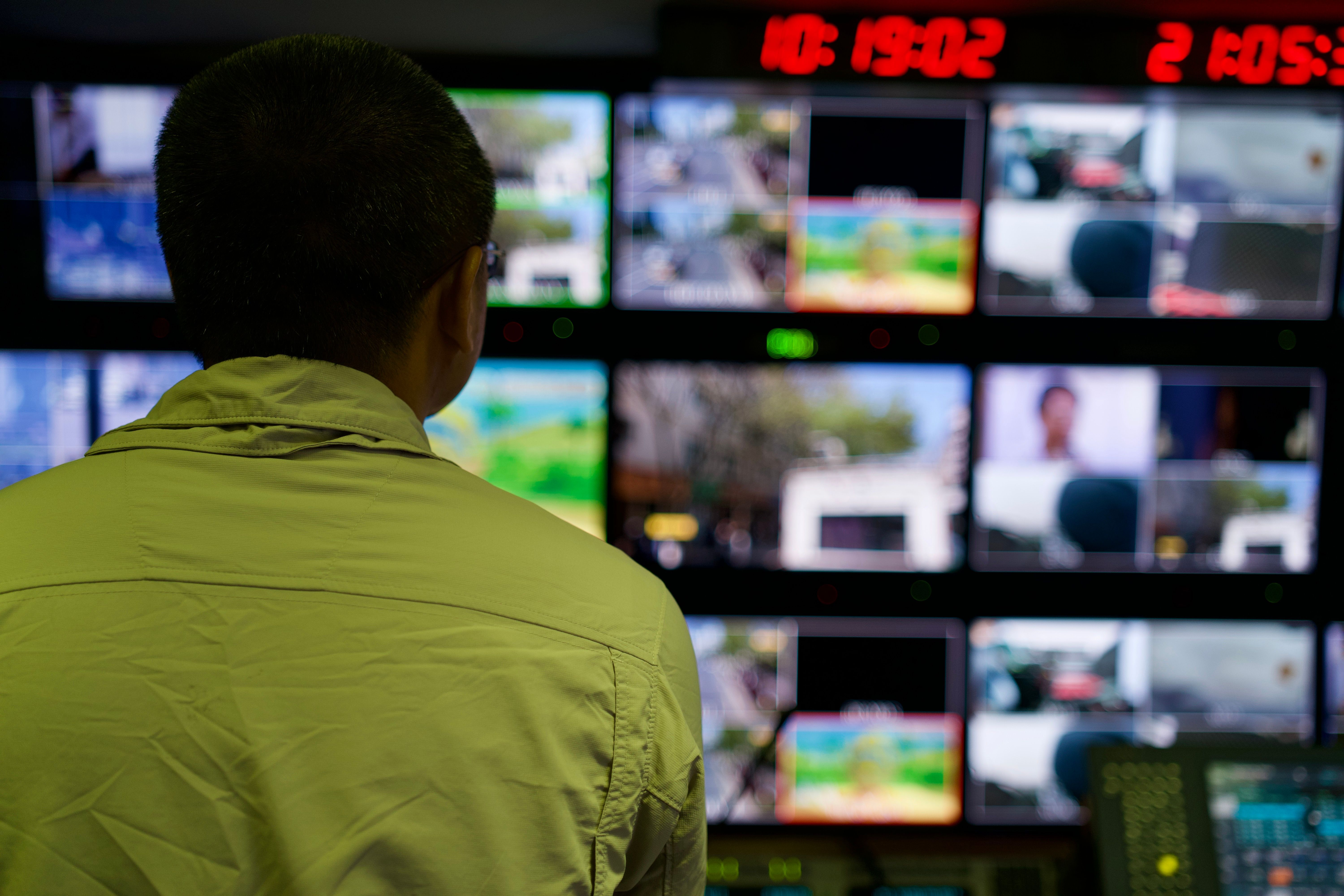 Investigator in a control room monitoring multiple video screens for digital evidence review